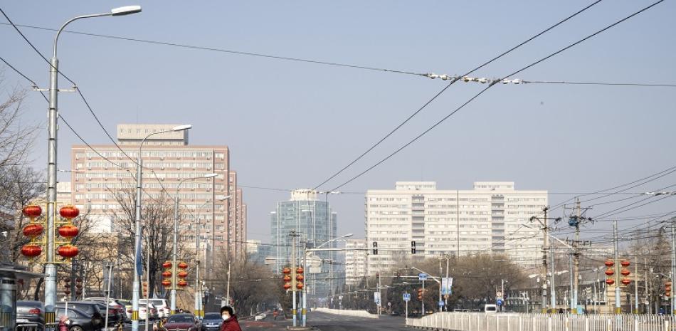 Una mujer que lleva un cubrebocas cruza una calle casi vacía en Pekín el 9 de febrero de 2020. (Giulia Marchi/The New York Times)
