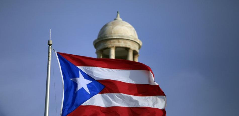 Fotografía de archivo del 29 de julio de 2015 de la bandera puertorriqueña ondeando frente al Capitolio de Puerto Rico en San Juan. (AP Foto/Ricardo Arduengo, archivo)
