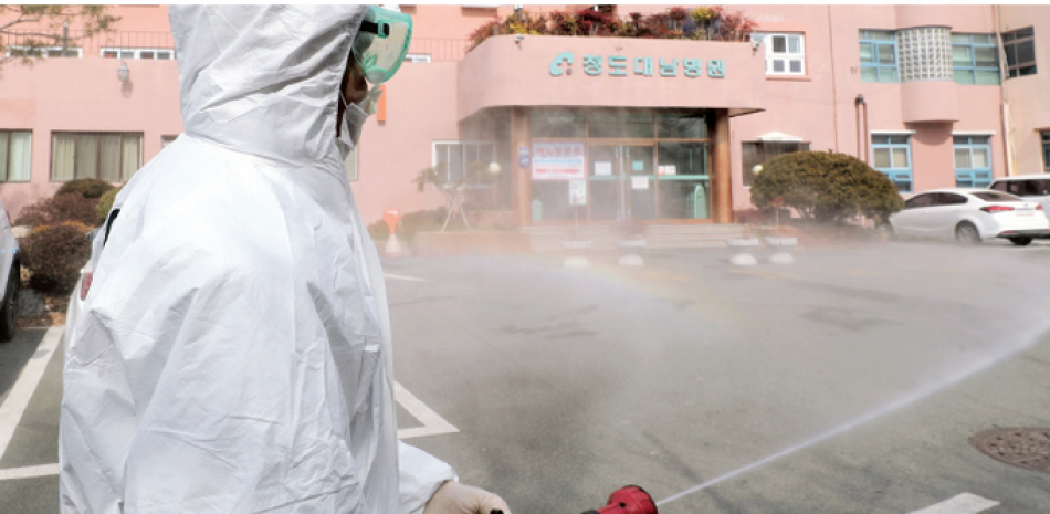 Trabajadores con equipo protector rocian con desinfectante el popular mercado de Namdaemun de Seúl, en el marco de esfuerzos para evitar la propagación del coronavirus. AP