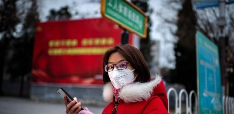 Mujer usa mascarilla en China para protegerse del coronavirus. / AFP