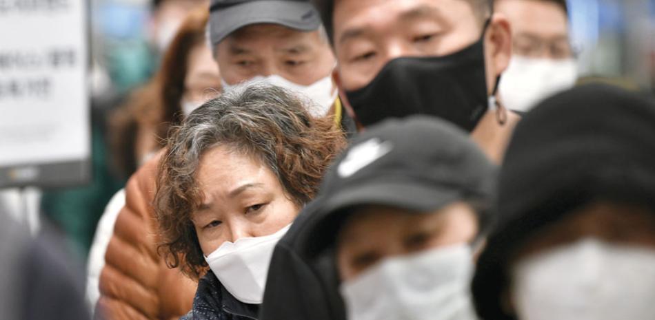 La gente espera turno para comprar máscaras faciales en una tienda minorista de la ciudad Daegu, en Corea del Sur. / AFP