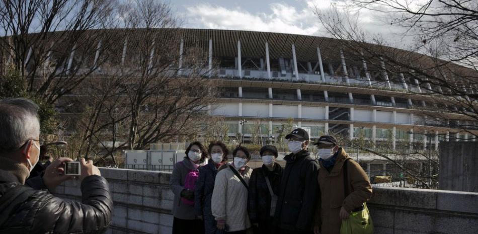 Grupo de turistas se toman una foto frente al estadio donde se inaugurarán los Juegos Olímpicos.