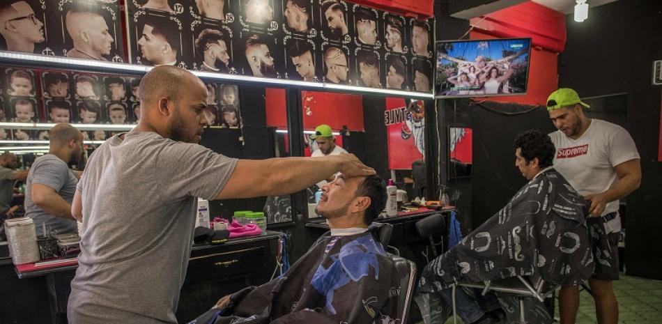 Dos migrantes cubanos cortan el pelo en una barbería de Tapachula, México, el 6 de febrero de 2020. (Daniele Volpe/The New York Times)