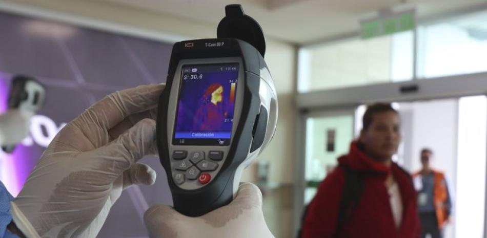 Personal de Ministerio de Salud de Quito, inspecciona la temperatura corporal de los viajeros. Foto: Ap.