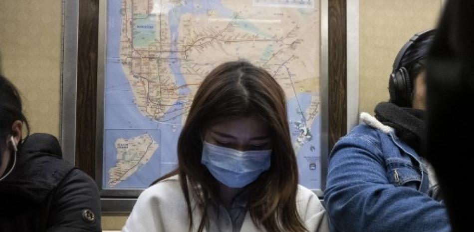 Una mujer usa una máscara mientras viaja en metro en Manhattan el 5 de marzo de 2020 en la ciudad de Nueva York. Johannes EISELE / AFP