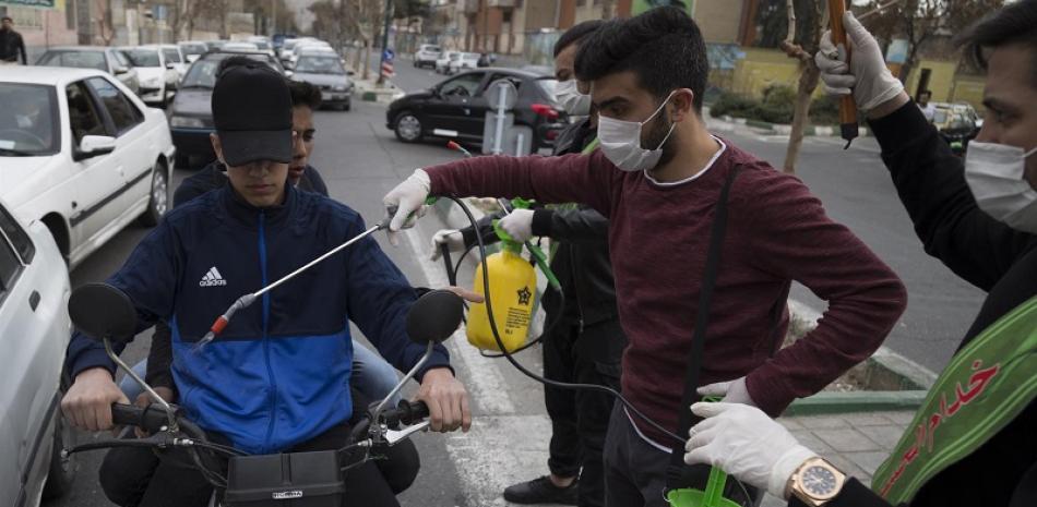 Personas desinfectan motorista en las calles de Teherán. / EP