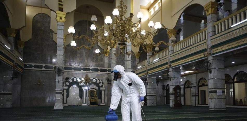 Un operario rocía desinfectante como medida de protección contra el coronavirus antes del rezo del viernes en una mezquita en Yakarta, Indonesia, el 13 de marzo de 2020. (AP Foto/Dita Alangkara)