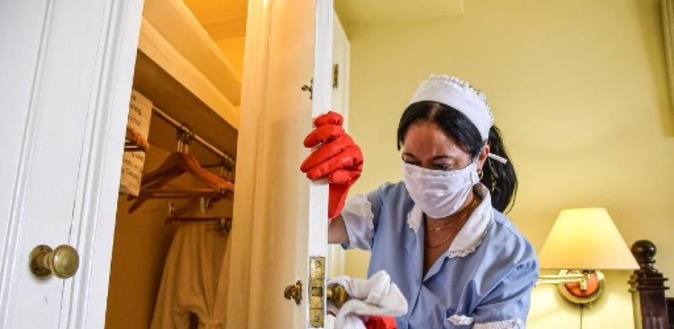 Empleada del Hotel Cubano Nacional limpia y desinfecta una habitación ocupada por turistas, como medida preventiva frente a la pandemia mundial del coronavirus, en La Habana. STR/AFP.