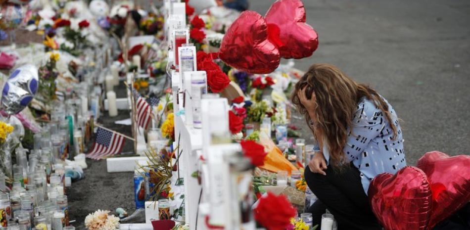 Gloria Garcés se arrodilla frente a un altar improvisado en el lugar donde ocurrió una masacre en un complejo comercial en El Paso, Texas, el martes 6 de agosto de 2019. (AP Foto/John Locher)