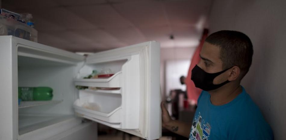 Ángel Ruiz muestra su congelador vacío en su casa, donde él y su esposa, Ivelisse Ríos, viven con sus dos hijos, el 29 de abril de 2020, en San Juan. La crisis alimentaria se está profundizando en Puerto Rico debido a la pandemia de coronavirus. (AP Foto/Carlos Giusti)