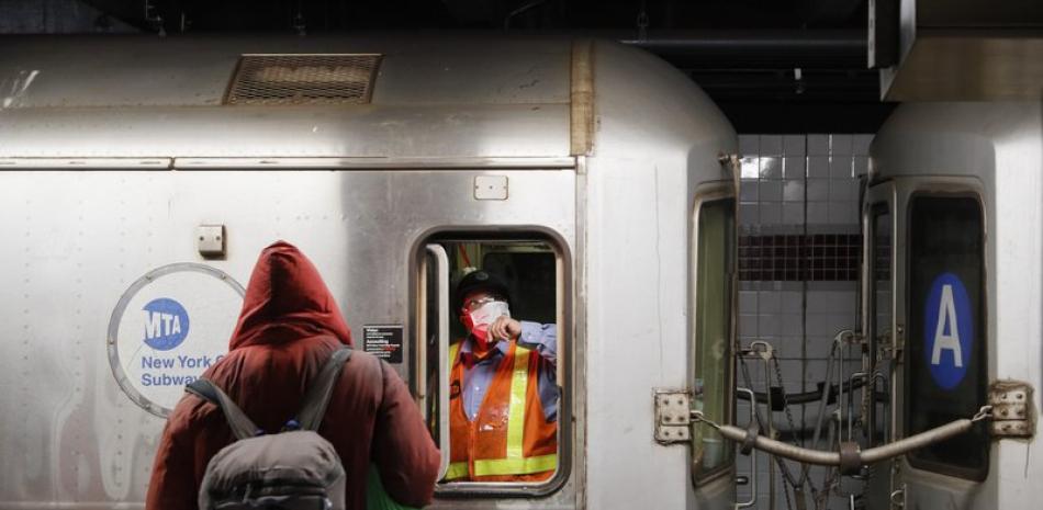 Un empleado de la Autoridad Metropolitana del Transporte (MTA) espera en el área de conductores de un vagón del metro mientras agentes de la policía de Nueva York y la MTA despiertan a pasajeros dormidos y los dirigen a la salida de la estación 207th Street A-train el jueves 30 de abril de 2020 en Manhattan, Nueva York. (AP Foto/John Minchillo)