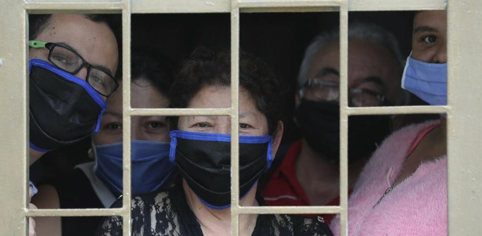 Una familia mira desde la ventana de su casa antes de recibir cajas de comida gratis durante la cuarentena para evitar la propagación del nuevo coronavirus en Bogotá, Colombia. (AP Foto / Fernando Vergara).