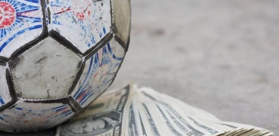Una pelota de fútbol junto a un fajo de dinero, foto de archivo. / EFE