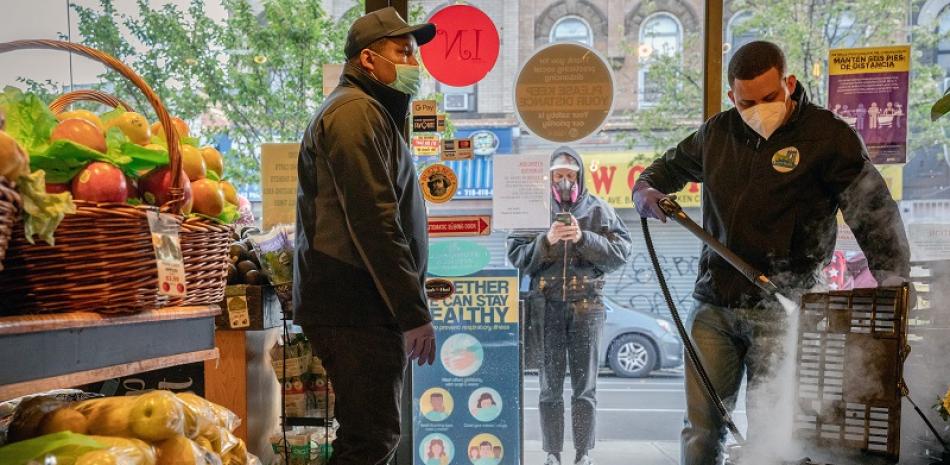 Un empleado desinfecta las canastas para las compras en City Fresh Market en Brooklyn el 16 de abril de 2020. (Juan Arredondo/The New York Times)