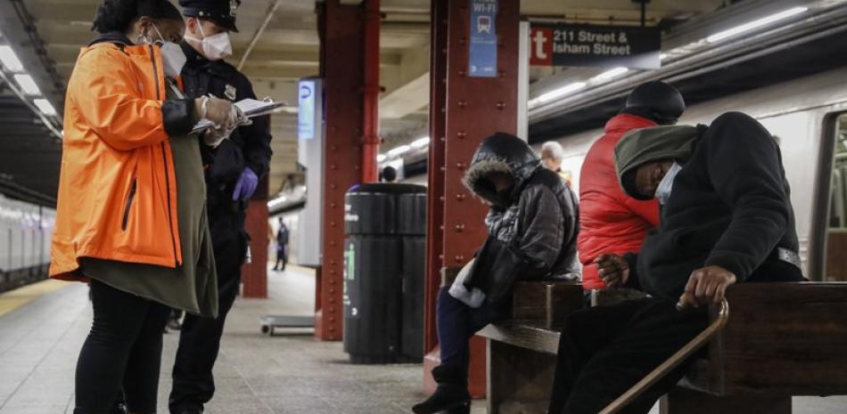En esta foto de archivo del 30 de abril de 2020, personal municipal de Nueva York asiste a indigentes que duermen en estaciones del metro. (AP Foto/John Minchillo, File)