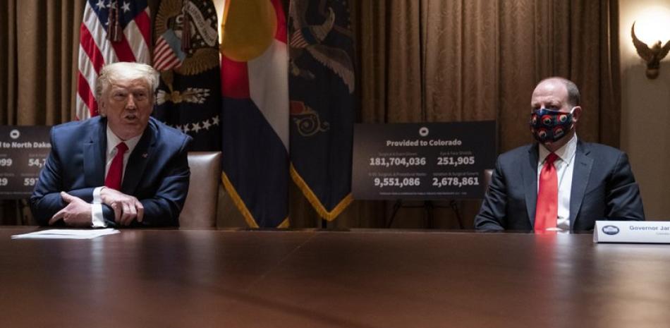 El presidente Donald Trump habla en una reunión con el gobernador de Colorado Jared Polis, a la derecha, el miércoles 13 de mayo de 2020 en torno a la respuesta al coronavirus, en la Sala del Gabinete de la Casa Blanca en Washington. (AP Foto/Evan Vucci).