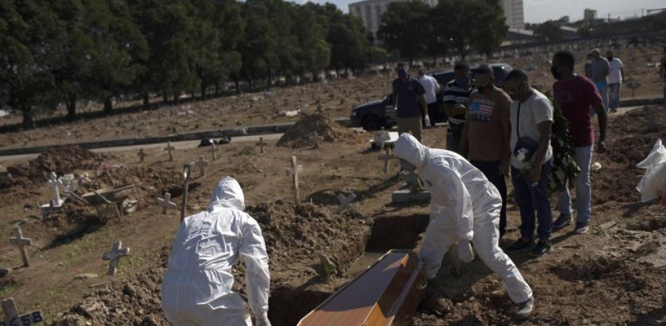 Empleados de un cementerio con trajes especiales para protegerse del coronavirus entierran el miércoles 20 de mayo de 2020 a Amanda da Silva, de 22 años, que falleció de COVID-19, en el cementerio de Caju, en Río de Janeiro. (AP Foto/Silvia Izquierdo)