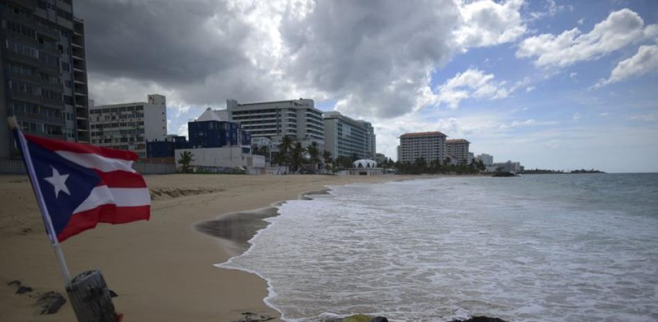 Una bandera puertorriqueña ondea en una playa vacía en Ocean Park el jueves 21 de mayo de 2020, en San Juan, Puerto Rico. (AP Foto/Carlos Giusti)