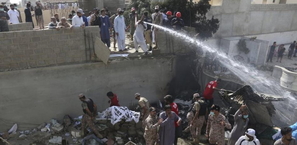 Soldados y voluntarios ayudan en las labores de emergencia en el sitio donde se estrelló un avión de pasajeros en Karachi, Pakistán, el viernes 22 de mayo de 2020. (AP Foto/Fareed Khan)