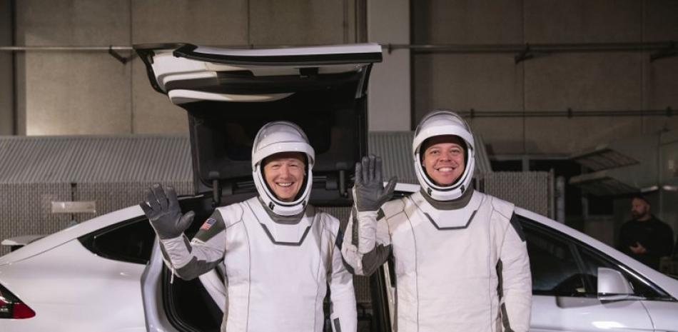 En esta fotografía del viernes 17 de enero de 2020 proporcionada por la NASA, los astronautas Doug Hurley (izquierda) y Robert Behnken posan frente al automóvil eléctrico Model X de Tesla durante un ensayo de lanzamiento en el Centro Espacial Kennedy, en Cabo Cañaveral, Florida. (Kim Shiflett/NASA vía AP)