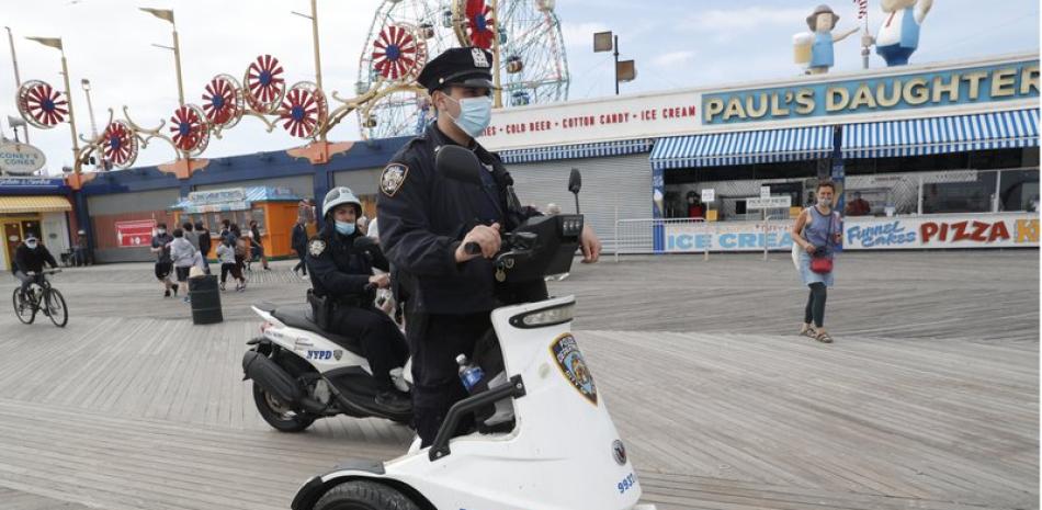 Policías circulan por Riegelmann Boardwalk en Coney Island el domingo 24 de mayo de 2020 para vigilar que la gente cumpla con las medidas de distanciamiento social debido al coronavirus, en Nueva York. (AP Foto/Kathy Willens)