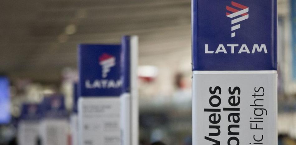 ARCHIVO - En esta imagen de archivo del 25 de julio de 2016, una empleada de LATAM Airlines junto a los mostradores de facturación en el aeropuerto de Santiago de Chile. (AP Foto/Esteban Félix, Archivo)