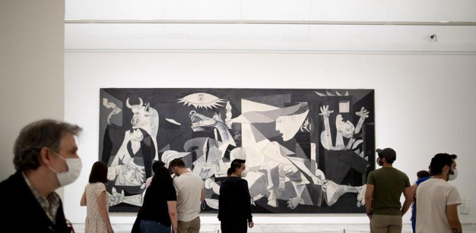 Visitantes contemplan el cuadro "Guernica" de Picasso en el Museo Reina Sodía de Madrid, que reabrió al público el sábado 6 de junio de 2020. También reabrieron el Museo del Prado y el Thyssen-Bornemisza. (AP Foto/Manu Fernández)