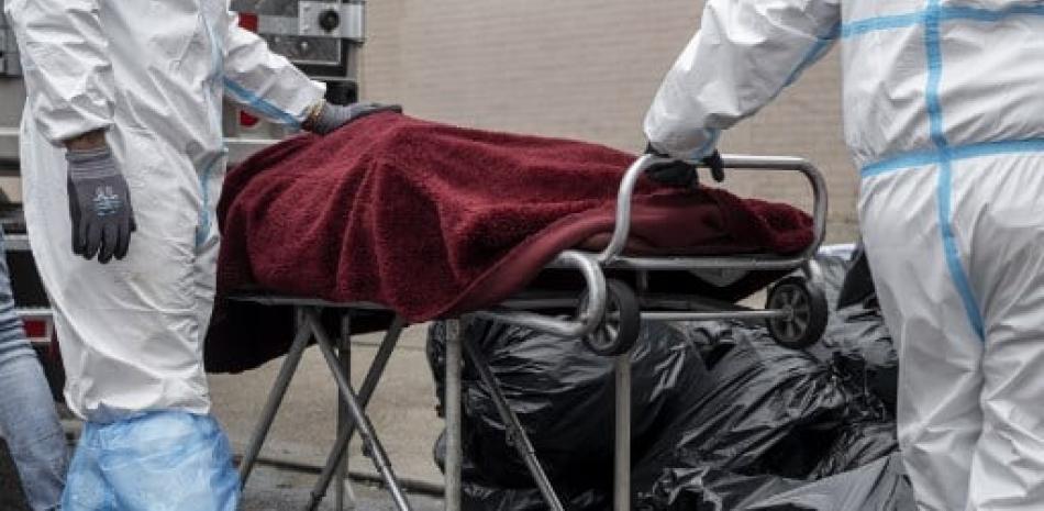 Personas transportan el cuerpo de un fallecido en una camilla frente a una funeraria en Brooklyn, Nueva York.  Johannes Eisele/AFP.