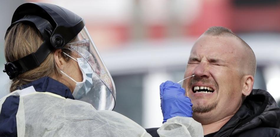 Imagen de archivo del 17 de abril de 2020, un hombre reacciona mientras personal médico hace pruebas a diagnósticas de coronavirus en un puesto en el estacionamiento de un supermercado en Christchurch, Nueva Zelanda. (AP Foto/Mark Baker, Archvo).