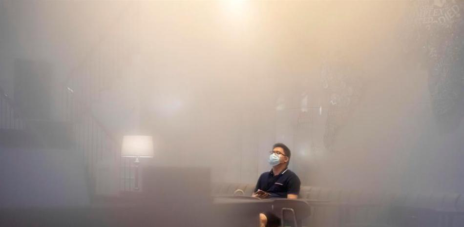 Un hombre con una máscara facial se sienta en un café como se ve a través de una ventana empañada debido a la humedad en Guangzhou, provincia de Guangdong, China, el 31 de mayo de 2020. Las personas en Guangzhou vuelven a la vida diaria normal a medida que la ciudad comienza a aliviar sus medidas de contención de coronavirus después de COVID -19 brote en China, mientras que el sur de China ha estado empapado por la lluvia continua durante las últimas 2 semanas causando inundaciones en toda la provincia de Guangdong. (Inundaciones) EFE / EPA / ALEX PLAVEVSKI