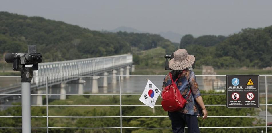 Una visitante con una bandera surcoreana utiliza los prismáticos para ver el Norte, en el Imjingak Pavilion en Paju, Corea del Sur, el 9 de junio de 2020. (AP Foto/Lee Jin-man)