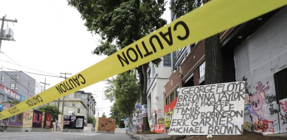 Un cartel con los nombres de víctimas de la violencia policial es exhibido en un área acordonada el sábado 20 de junio de 2020, en la zona conocida como CHOP (Capitol Hill Occupied Protest) que ha sido el epicentro de las protestas en Seattle. (AP Foto/Ted S. Warren)