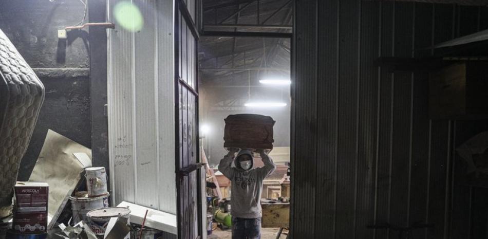 Un fabricante de ataúdes lleva un féretro en la fábrica Bergut Funeral Services en Santiago de Chile. (Foto AP/Esteban Félix)