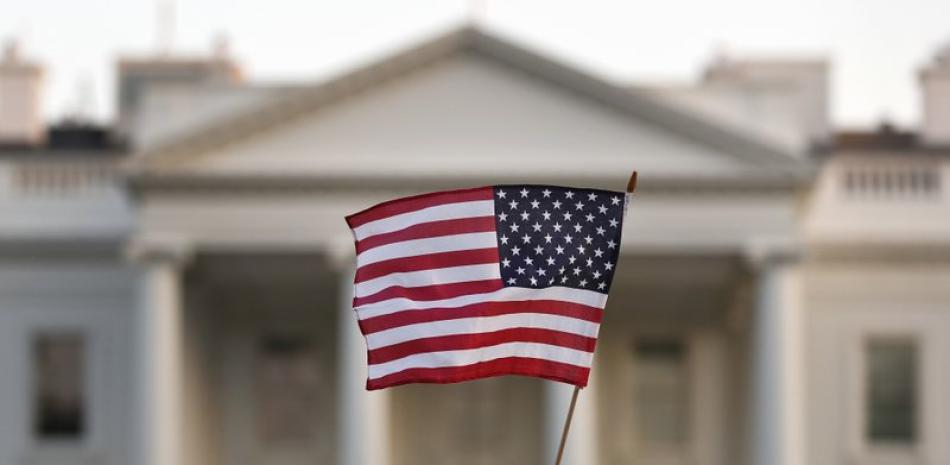 En esta fotografía del 5 de septiembre de 2017 una persona ondea una bandera estadounidense frente a la Casa Blanca, en Washington. (AP Foto/Carolyn Kaster, archivo).