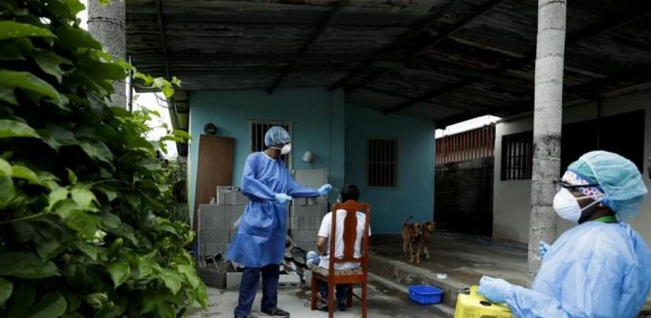 Un trabajador del Ministerio de Salud de Panamá toma una muestra a un residente mientras su equipo va de casa en casa para efectuar pruebas rápidas de COVID-19 el lunes 15 de junio de 2020, en el vecindario Nuevo Tocumen, en las afueras de la Ciudad de Panamá. (Foto AP/Arnulfo Franco)