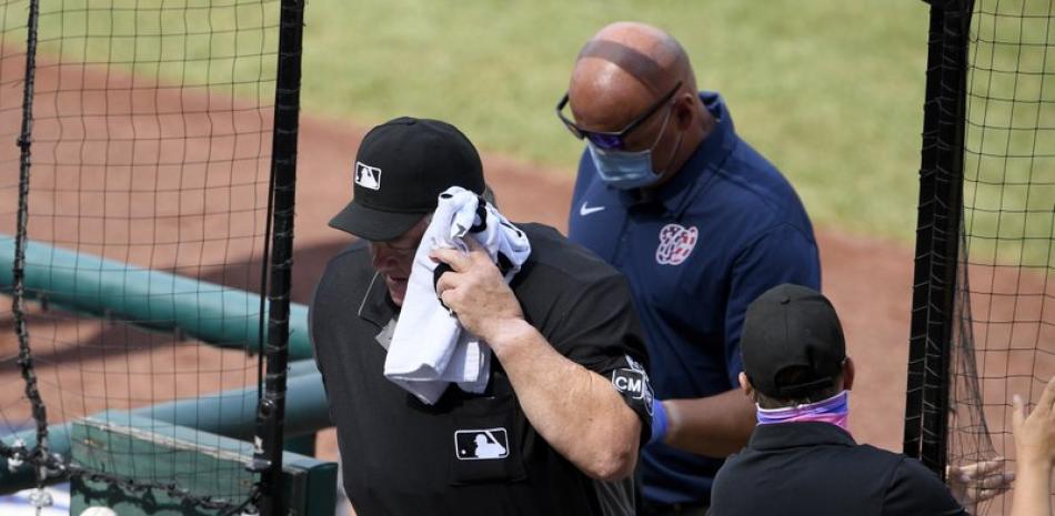 El umpire del plato Joe West es conducido fuera del terreno para recibir atención médica, luego de ser herido por un batazo accidental durante el encuentro de este jueves entre los Nacionales de Washington y los Azulejos de Toronto.