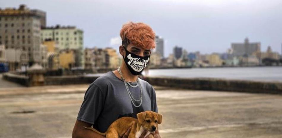 Poo Alejandro Padrun, 15 años, usa una mascarilla como protección contra el nuevo coronavirus mientras posa con su perro en el Malecón de La Habana, Cuba, el miércoles 22 de julio de 2020. (AP Foto / Ramon Espinosa)