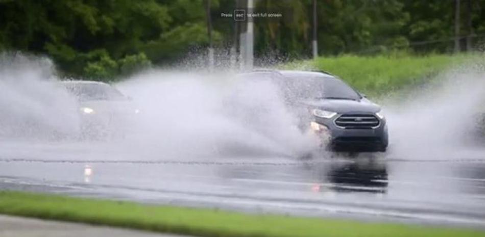 En esta imagen, tomada de un video, autos son conducidos por una carretera inundada en Canovanas, Puerto Rico, el 30 de julio de 2020. (AP Foto)