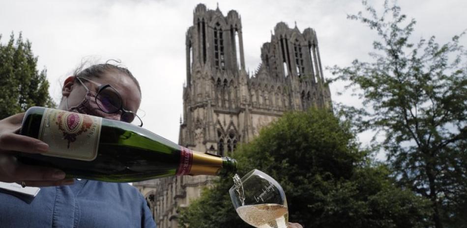 Una camarera sirve champaña en el restaurante La Grande Georgette frente a la catedral de Reims, en la región francesa de Champaña, 28 de julio de 2020. (AP Foto/Francois Mori)