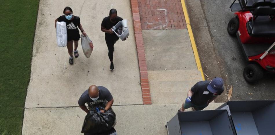 Varias personas transportan materiales el viernes 31 de julio de 2020 al comenzar a llegar los estudiantes para el semestre de otoño en la Universidad Estatal de Carolina del Norte, en la ciudad de Raleigh. (AP Foto/Gerry Broome)