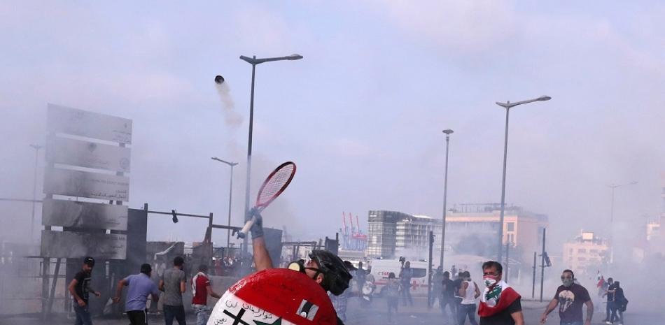 Protestas en Beirut, Líbano. Una persona golpea una aparente bomba lacrimógena con una raqueta. / AP