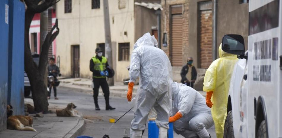 Trabajadores de salud con equipo para protegerse del coronavirus desinfectan el cadáver de un vendedor ambulante el sábado 25 de julio de 2020 en el vecindario Cerro San Miguel, en Cochabamba, Bolivia. (AP Foto/Dico Solís)