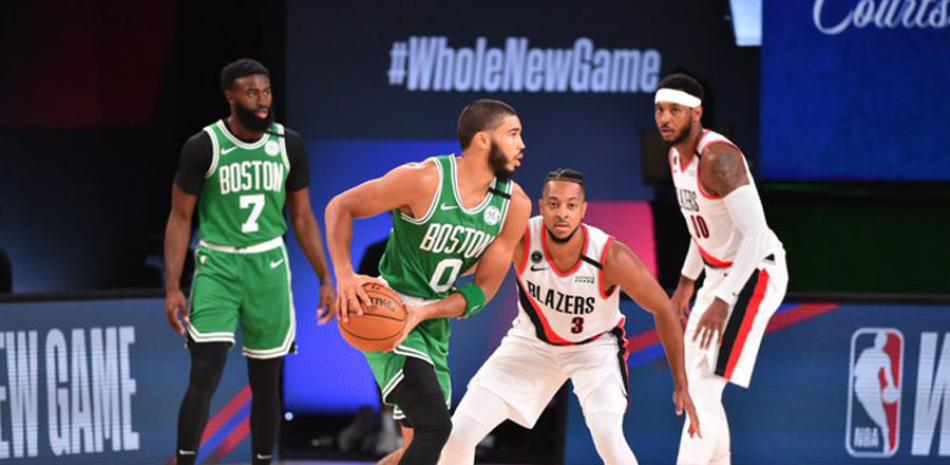 Jayson Tatum, de los Celtics, protege el balón ante la defensa de CJ McCollum, de Portland, en acción del partido de ayer en el baloncesto de la NBA.