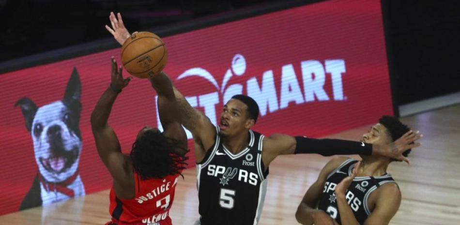 El escolta de los San Antonio Spurs, Dejounte Murray (5), se defiende contra el escolta de los Houston Rockets, Chris Clemons (3), durante el segundo juego de baloncesto de la NBA este martes en Lake Buena Vista, Florida.
