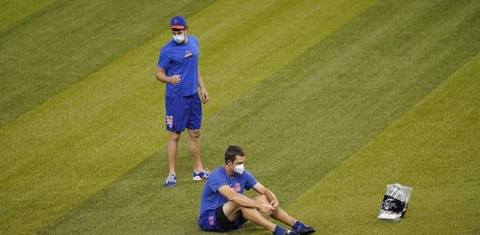 Los jugadores de los Mets de Nueva York se sientan en el campo antes de un partido de béisbol contra los Marlins de Miami, este jueves en Miami.