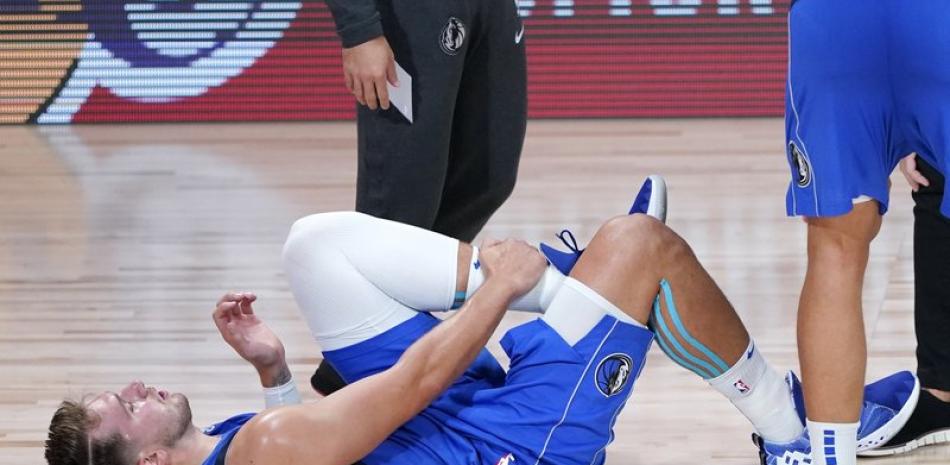 Luka Doncic (77) de los Dallas Mavericks se agarra la pierna izquierda después de lesionarse durante la segunda mitad de un juego de playoffs de primera ronda de baloncesto de la NBA contra Los Angeles Clippers este viernes.