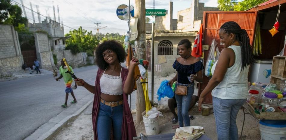 Semi Kaefra Alisha Fermond, una mujer transexual, sonríe tras recibir un caramelo de vendedores callejeros mientras camina hacia el centro Kay Trans Haití para celebrar su 24 cumpleaños, en Puerto Príncipe, Haití, el 7 de agosto de 2020. Los prejuicios y la discriminación contra las personas transexuales son habituales en Haití, pero al menos una organización les ofrece un refugio en el que pueden sentirse bienvenidas y aceptadas. (AP Foto/Dieu Nalio Chery)