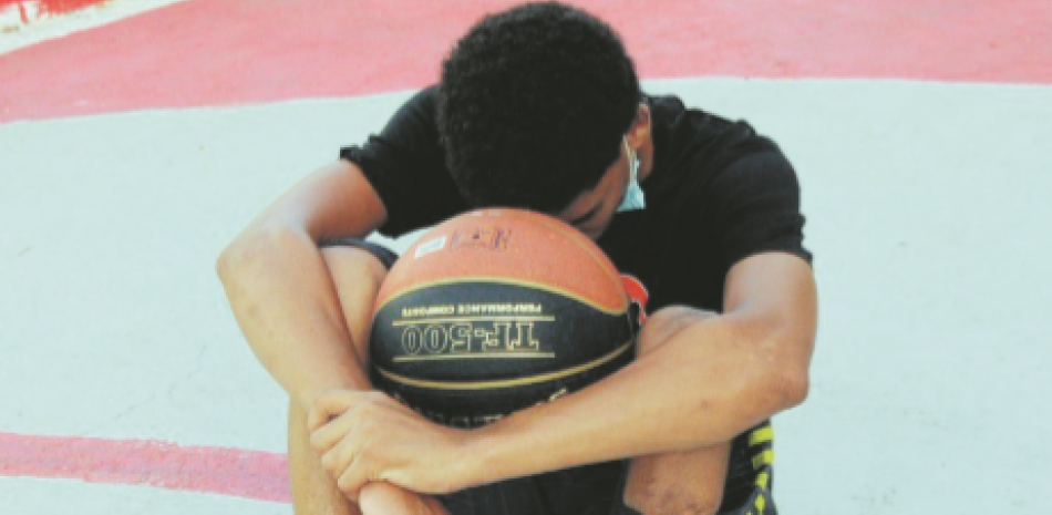 El basquetbolista Jefferson Alcántara en un momento de descanso y reflexión en la cancha de la escuela Eugenio Deschamps.