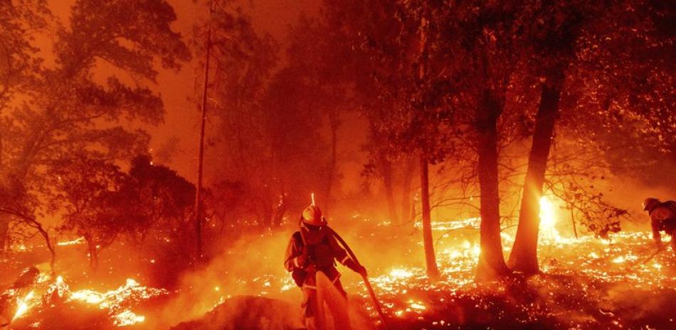 En esta fotografía del 7 de septiembre de 2020, bomberos combaten el incendio Creek que amenaza diversas casas en el vecindario de Cascadel Woods, en el condado Madera, en California. (AP Foto/Noah Berger).