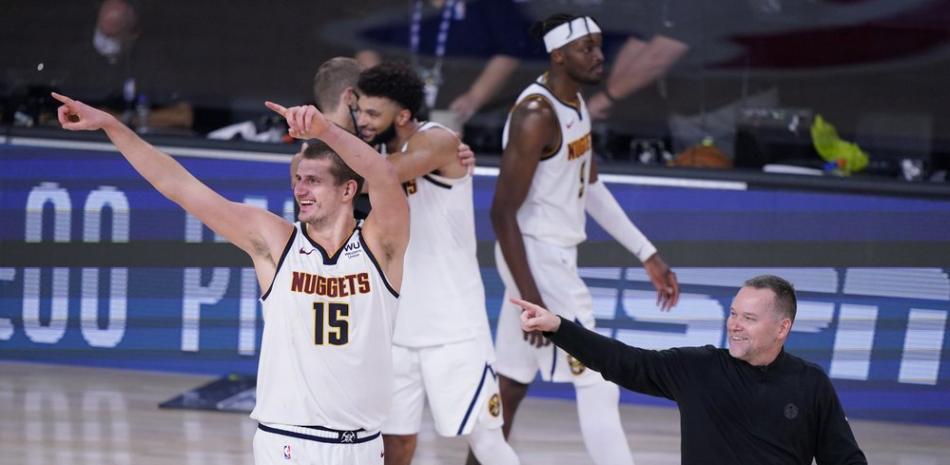 El centro de los Denver Nuggets, Nikola Jokic (15), y el entrenador en jefe de los Denver Nuggets, Michael Malone, a la derecha, celebran su victoria sobre Los Angeles Clippers en un partido de baloncesto de semifinales de la conferencia de la NBA el martes.